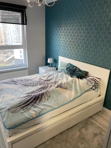 a bed in a bedroom with a blue wall at Nowoczesny apartament Gdańsk Spektrum blisko morza in Gdańsk