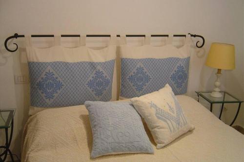 un letto con cuscini bianchi e blu di Golfo di Marinella stupendo bilocale vista mare a Marinella