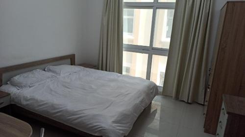 a white bed in a room with a window at Furnished Studio Apartments for rent in Dubai in Dubai