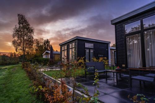 a black house with a patio and a garden at River Cabin 4 people in Zuna