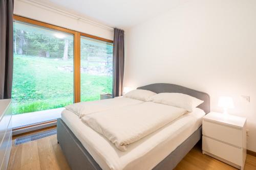 ein Schlafzimmer mit einem Bett und einem großen Fenster in der Unterkunft Residenz Cuolm Liung 52 in Laax