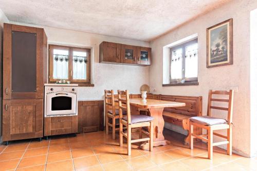a kitchen with a table and chairs and a stove at Baita Rustica immersa nel verde in Roncone