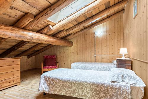 a bedroom with two beds and a wooden ceiling at Baita Rustica immersa nel verde in Roncone