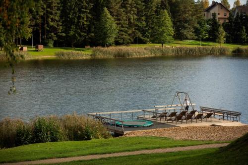 a dock with chairs and a playground on a lake at Vila Kelmyne in Molėtai
