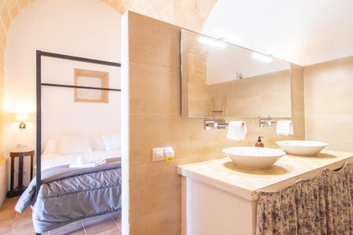 uma casa de banho com 2 lavatórios e uma cama num quarto em Finca Agroturismo Es Pujol em Santanyi