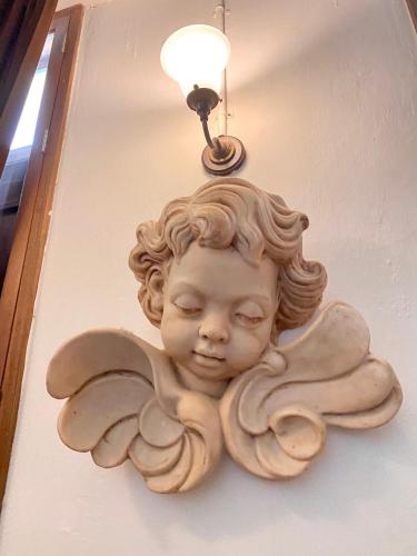 a white angel statue on a wall with a light at 103 - Bed and Brews in Bangkok