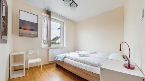 a white bedroom with a bed and a desk at Bursztynowe Osiedle Jantar, Sun & Snow in Jantar