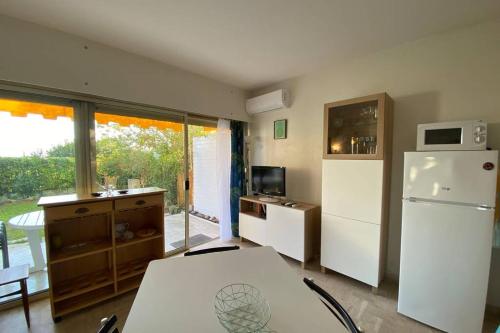 Il comprend une cuisine équipée d'un réfrigérateur blanc, d'une table et d'une fenêtre. dans l'établissement C037-Nice studio with garden and parking - Near beach, à Cannes