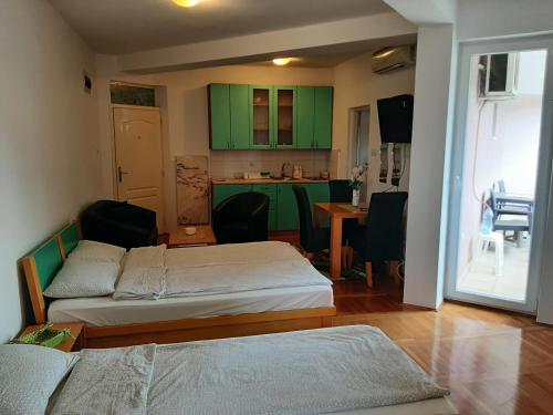 a room with two beds and a kitchen with green cabinets at Apartman Zivanovic1 in Banja Koviljača