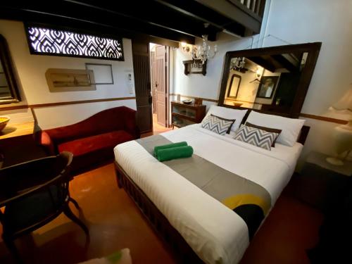 a bedroom with a large bed and a red couch at 103 - Bed and Brews in Bangkok