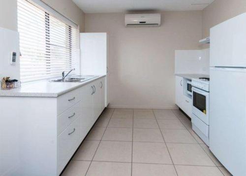 a kitchen with white cabinets and white appliances at Quality Hotel Robertson Gardens in Brisbane