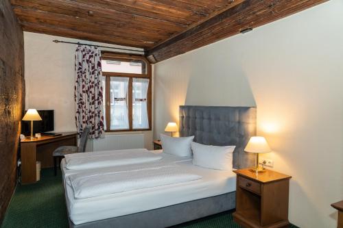 a bedroom with two beds and a desk and a window at Ringhotel Schlossberg in Neustadt