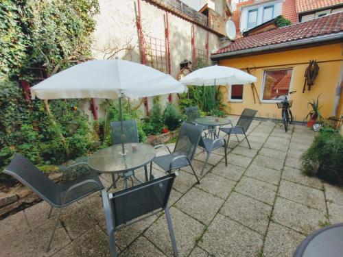 a patio with two tables and chairs and umbrellas at Pension Bergstube in Bad Langensalza
