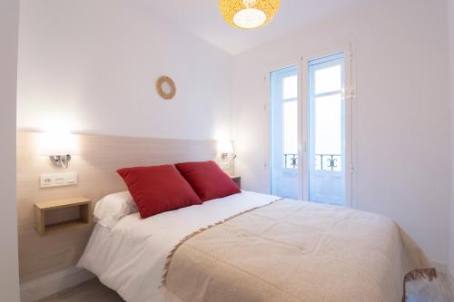 Una cama blanca con almohadas rojas en un dormitorio en MOLINO CORTEZA EXCELENTE SEGUNDO Granada centro, en Granada