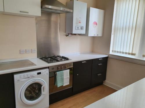 a kitchen with a stove and a washing machine at Flat 1 Castlebank house Flats in Dingwall