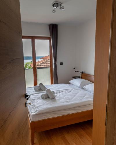 a bedroom with a bed with white sheets and a window at Apartment Rustica in Portorož