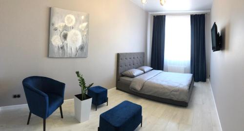um quarto com uma cama e uma cadeira azul em Люкс апартаменти в центрі Жк Театральний em Rivne