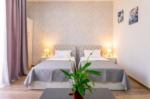 a bedroom with two beds and a plant at Hotel Rustaveli Kutaisi in Kutaisi