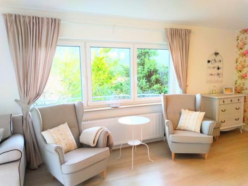 a living room with two chairs and a table and windows at Romantic Style Apartment Titisee-Neustadt in Titisee-Neustadt