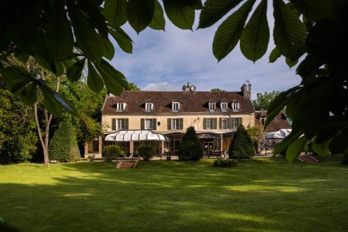 a large house with a large yard with green grass at Les Demeures de Varennes, BW Signature Collection in Varennes-Jarcy