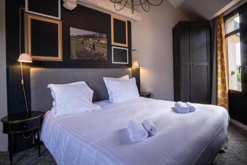 a bedroom with a large white bed with slippers on it at Les Demeures de Varennes, BW Signature Collection in Varennes-Jarcy