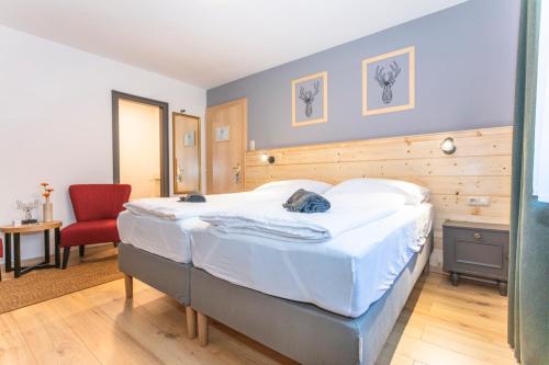 sypialnia z dużym łóżkiem i czerwonym krzesłem w obiekcie Sonnberg Lodge w mieście Maria Alm am Steinernen Meer