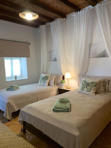 two beds in a room with white curtains at Althea Garden House in Hydra