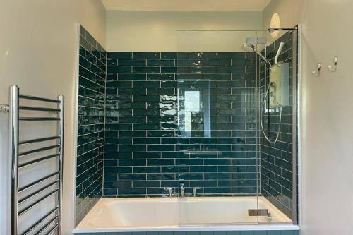 a green tiled bathroom with a tub and a shower at Kingsdale Head Cottage in Weathercote