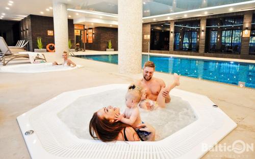 a man and a woman and a baby in a pool at Apartamenty BalticON Nadmorskie Tarasy in Kołobrzeg