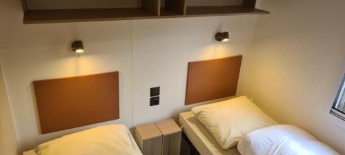 een kamer met 2 bedden en 2 verlichting aan de muur bij Mini-chalet - Vakantiepark 't Urkerbos in Urk