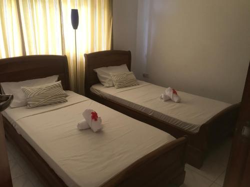 two beds in a hotel room with roses on them at Royale Self Catering Apartments in Anse Royale