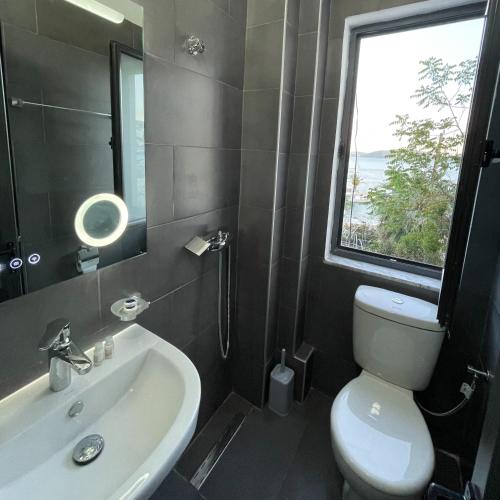 a bathroom with a sink and a toilet and a window at Villa Balbi 34 in Sarandë