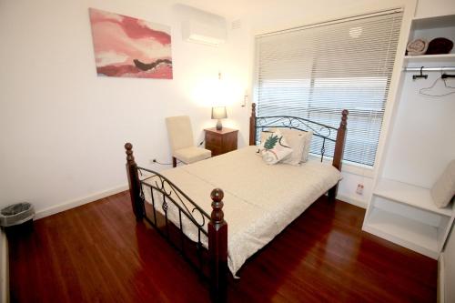 a bedroom with a bed and a chair and a window at Garden Guesthouse - Melbourne Airport Accommodation in Melbourne