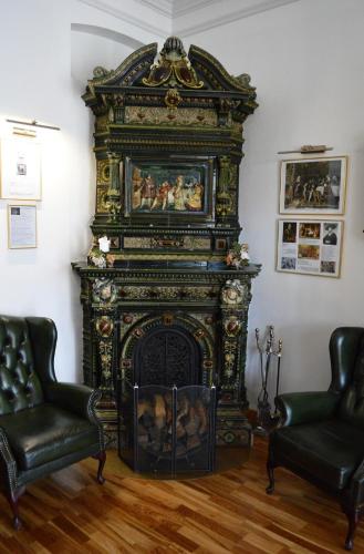 an ornate fireplace in a living room with two chairs at Sventes Muiža in Svente