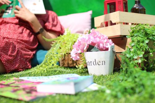 a woman sitting on the grass with flowers and a potted plant at T-Life Hostel in Longjing