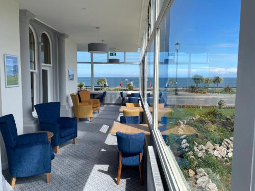 een wachtkamer met stoelen en tafels en uitzicht op de oceaan bij Hydro Hotel in Llandudno