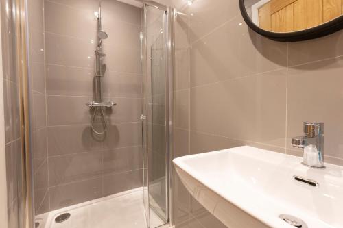 a shower with a glass door next to a white sink at Fletchers Rest in Whitby