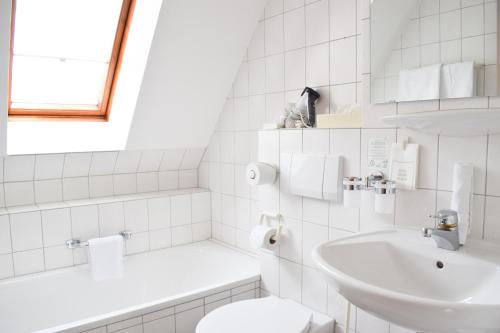 ein weißes Bad mit einem Waschbecken und einem WC in der Unterkunft Castell Hotel & Restaurant in Leinsweiler