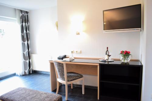 a hotel room with a desk and a tv at Castell Hotel & Restaurant in Leinsweiler