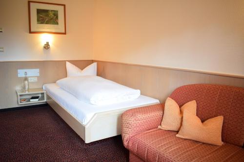 a bed and a chair in a room with a bed and a couch at Castell Hotel & Restaurant in Leinsweiler