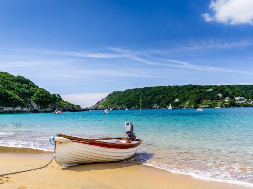 a small boat sitting on the sand on a beach at Two Hoots in Kingsbridge