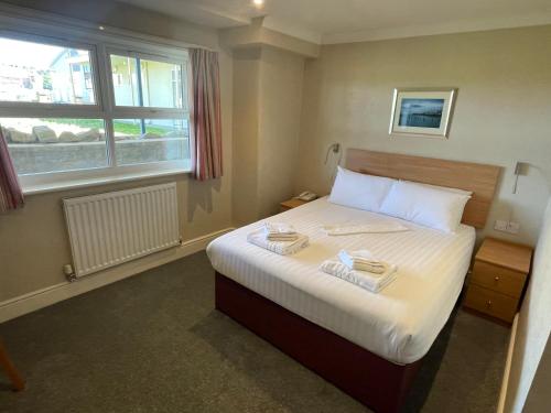 een slaapkamer met een bed met twee handdoeken erop bij Hydro Hotel in Llandudno