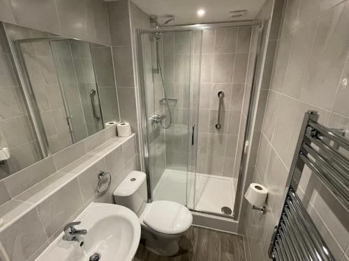 een badkamer met een douche, een toilet en een wastafel bij Hydro Hotel in Llandudno