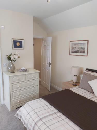 a bedroom with a bed and a dresser with a vase of flowers at Oaktree Lodge in Doncaster