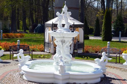 a white fountain in a park with birds on it at Sventes Muiža in Svente