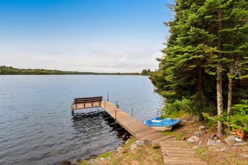 a dock with a bench and a boat on a lake at High Lake Hideaway in Boulder Junction