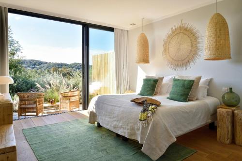 a bedroom with a large bed and a large window at Domaine de Peretti della Rocca in Figari