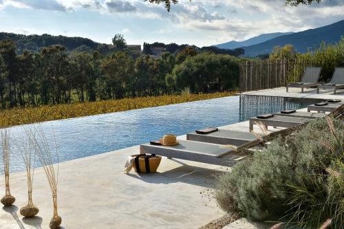a pool of water with tables and chairs on it at Domaine de Peretti della Rocca in Figari