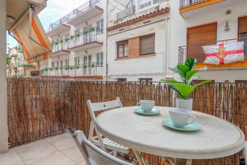 a table with two cups and chairs on a balcony at Gloria Apartment by Hello Homes Sitges in Sitges