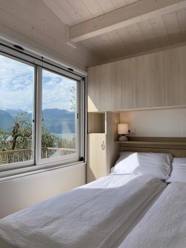 a bedroom with a bed and a large window at Camping Le Maior in Brenzone sul Garda